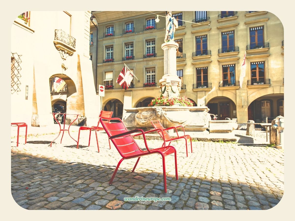 Red public chairs in front of Bern Cathedral and beside Mosesbrunnen in Bern, Switzerland